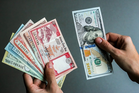 Hands holding nepalese and american currency (banknotes).の写真素材