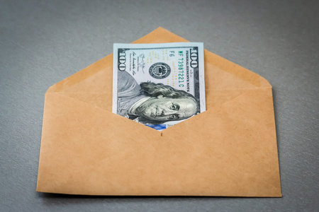 Closeup view of envelope with one hundred dollar banknote.