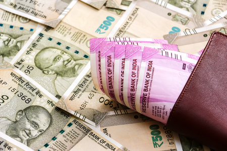Close up view of leather wallet with brand new indian 2000 rupees banknotes. 500 rupee banknotes in background.の写真素材