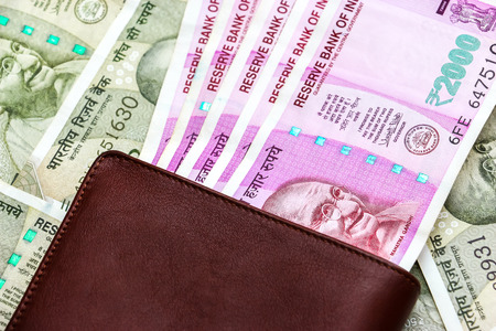 Close up view of leather wallet with brand new indian 2000 rupees banknotes. 500 rupee banknotes in background.の写真素材