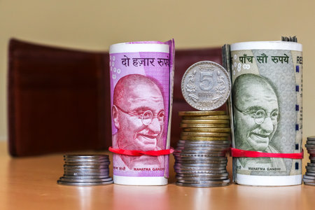 Close up view of indian rupees. Banknotes and stacked coins. Leather wallet in background.