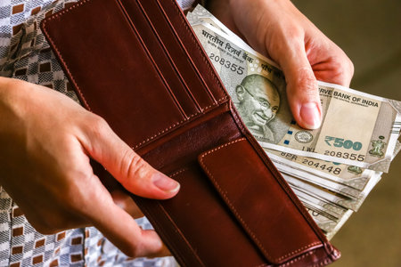 Woman's hands holding wallet with brand new indian 500 rupees banknotes.の写真素材