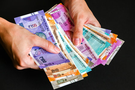 Woman's hands holding brand new indian 50, 100, 200, 500, 2000 rupees banknotes.