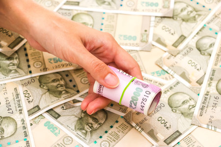 Female hands holding brand new 2000 indian rupees banknotes over 500 rupees banknotes background.