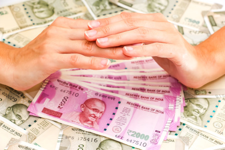 Close up view of female hands over brand new indian 500 and 2000 rupees banknotes.の写真素材