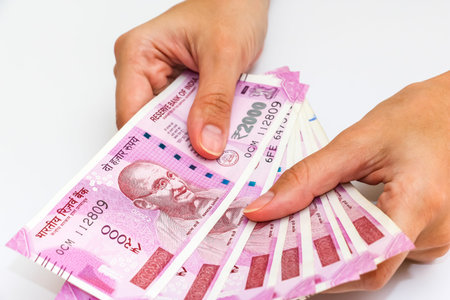 Female hands holding brand new 2000 indian rupees banknotes.