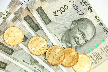 Close up view of brand new indian 500 rupees banknotes and coins on white background.