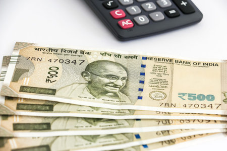 Close up view of calculator and brand new indian 500 rupees banknotes on white background.