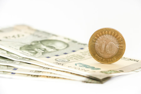 Close up view of brand new indian 500 rupees banknotes and coin on white background.