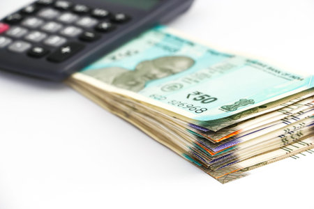 Close up view of calculator over  brand new indian 50, 100, 200, 500 rupees banknoteson white...