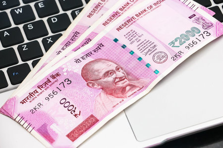 Close up view of brand new indian 2000 rupees banknotes and  laptop.