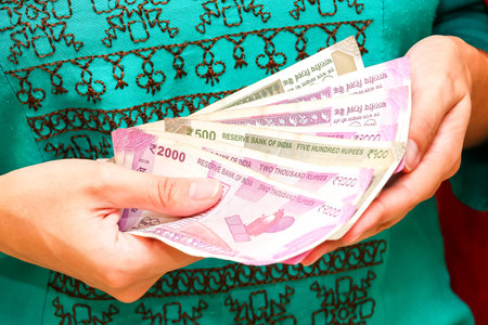 Female hands holding brand new indian 500 and 2000 rupees banknotes.