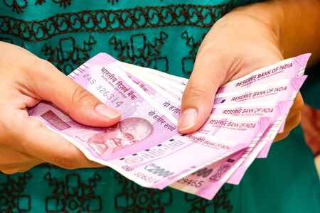 Female hands holding brand new indian 2000 rupees banknotes.の写真素材