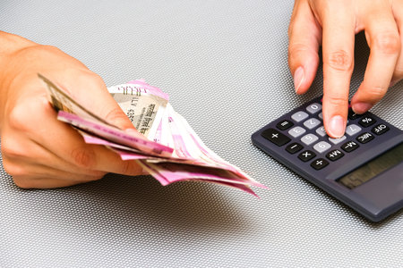 Female hands with brand new indian 500 and 2000 rupees banknotes and electronic calculator.