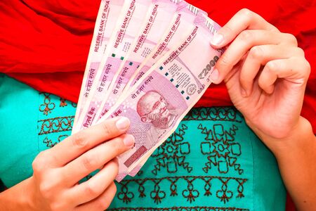 Female hands holding brand new indian 2000 rupees banknotes.の写真素材