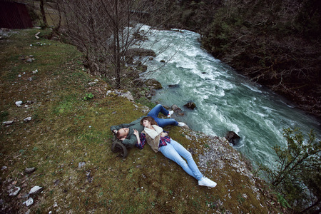The guy with the girl lying on a cliff by the river. In the mountains.の写真素材