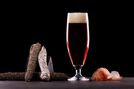 A glass of dark beer foam, Parma ham, expensive varieties of sausage. On black background. Place for logo.の写真素材