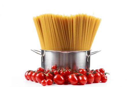 Pasta spaghetti in a metal pan in a large collum on a white background with tomatoes.の写真素材