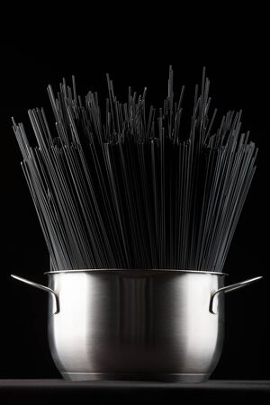 Black spaghetti pasta in a saucepan on a black background.の写真素材