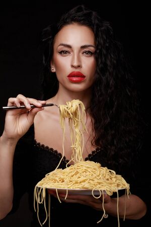 A beautiful girl eats with a fork spaghetti with red lips.の写真素材