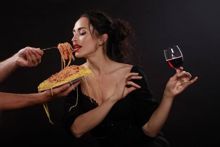 Beautiful girl eats spaghetti and drinks wineの写真素材