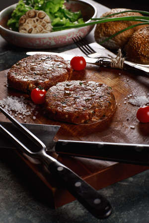 Raw Ground beef meat Burger steak cutlets with ingredients on the board.の写真素材