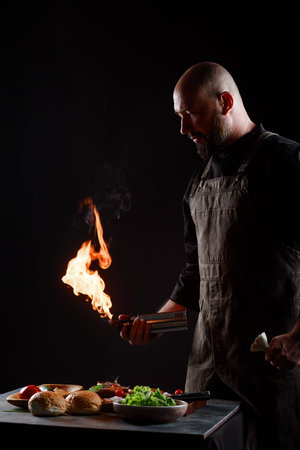 Cef cooks burgers, roasts meatballs on open fire.