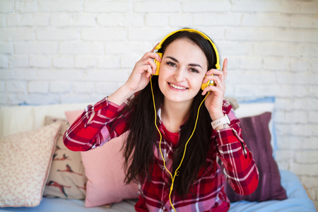 Beautiful young woman listening to music in headphones at homeの写真素材