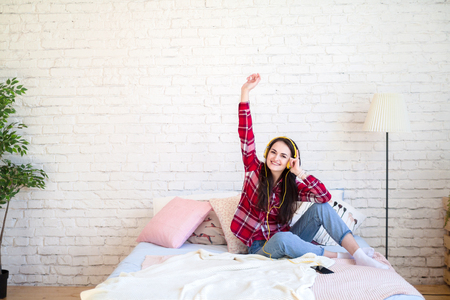 Beautiful young woman listening to music in headphones at homeの写真素材