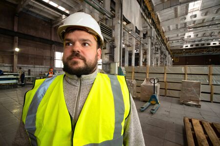 Bearded handsome smiling engineer worker, helmet and vestの写真素材