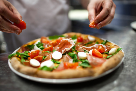 Closeup hand of chef baker in white uniform making pizza at kitchenの写真素材