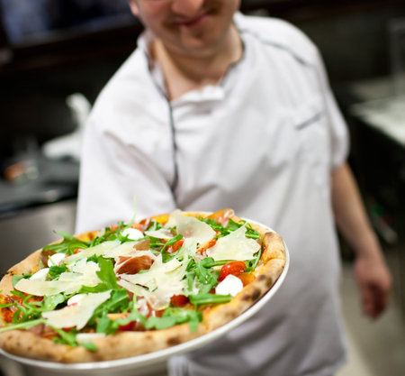The waiter of restaurant with a pizza in hands