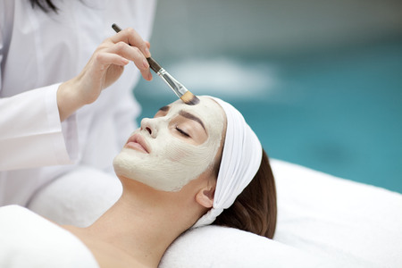 Close-up portrait of beautiful girl with a towel on her head applying facial maskの写真素材