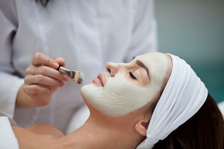 Close-up portrait of beautiful girl with a towel on her head applying facial mask