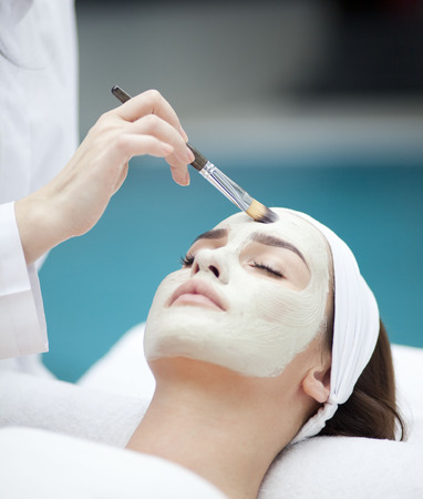Close-up portrait of beautiful girl with a towel on her head applying facial maskの写真素材