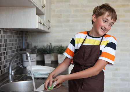 boy doing the dishes in the kitchenの写真素材