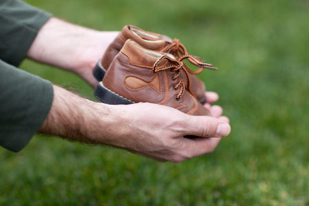 Dirty hands holding a pair of old childrens shoes