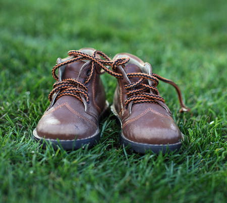 Dirty hands holding a pair of old childrens shoesの写真素材