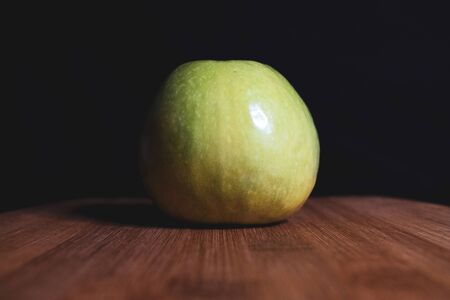 Green apple is lying on a wooden Board. Organic fruit. Healthy lifestyle. Sweet fruit. Vegetarian healthy food. Natural background. Dark background.の写真素材