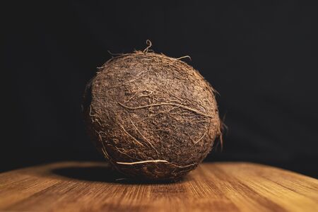 Coconut is lying on a wooden Board. Tasty tropical fruit. healthy nutrition. Diet concept. Concept design. Closeup of coconut. Healthy fresh nutrition. Vegetarian healthy food. Dark background.の写真素材