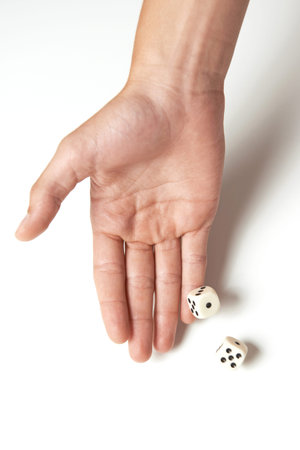 Hand throwing two dices on a white table