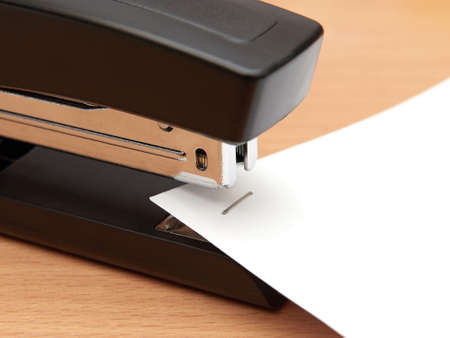 Closeup of a modern office stapler joining paper sheetsの写真素材