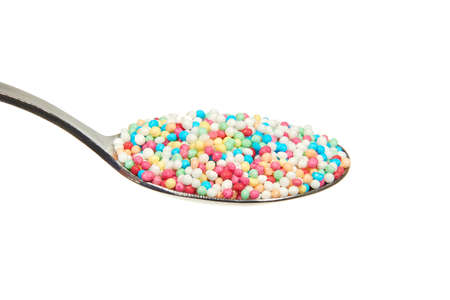 Multicolor nonpareils on a teaspoon on a white backgroundの写真素材