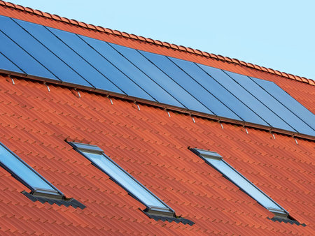 Flat plate solar thermal collectors on a red tile roof