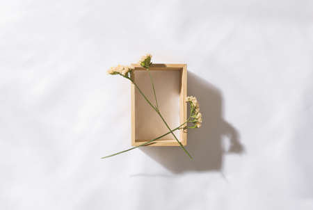 Top view of a wooden niche in voile fabric background with two flowers, with space for textの写真素材