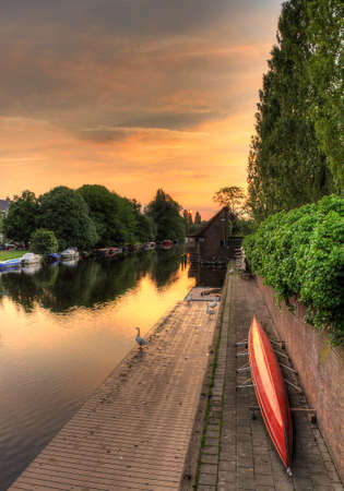 Early morning sunrise at the river with a boat on the shoreの写真素材
