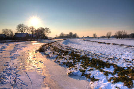 beautiful snowy river landscape at sunset in the Netherlandsの写真素材