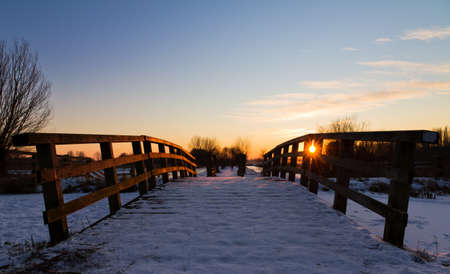 Snowy bridge in winter at sunsetの写真素材
