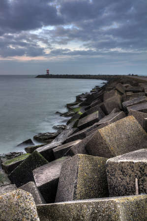 HDR image of the concrete blocks which form the jetty on a cloudy day at sunset in Scheveningen, Netherlandsのeditorial素材