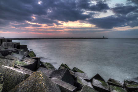 HDR image of the concrete blocks which form the jetty on a cloudy day at sunset in Scheveningen, Netherlandsのeditorial素材